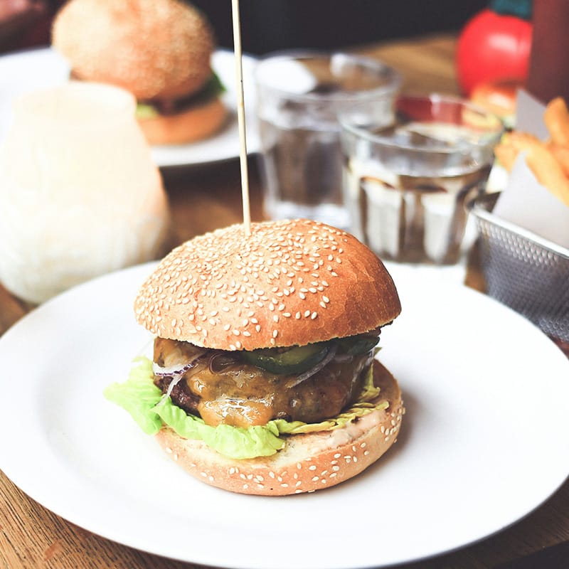 Close-up of a gourmet cheeseburger on a plate, illustrating Trillium Estates amenities with diverse dining experiences close to home.