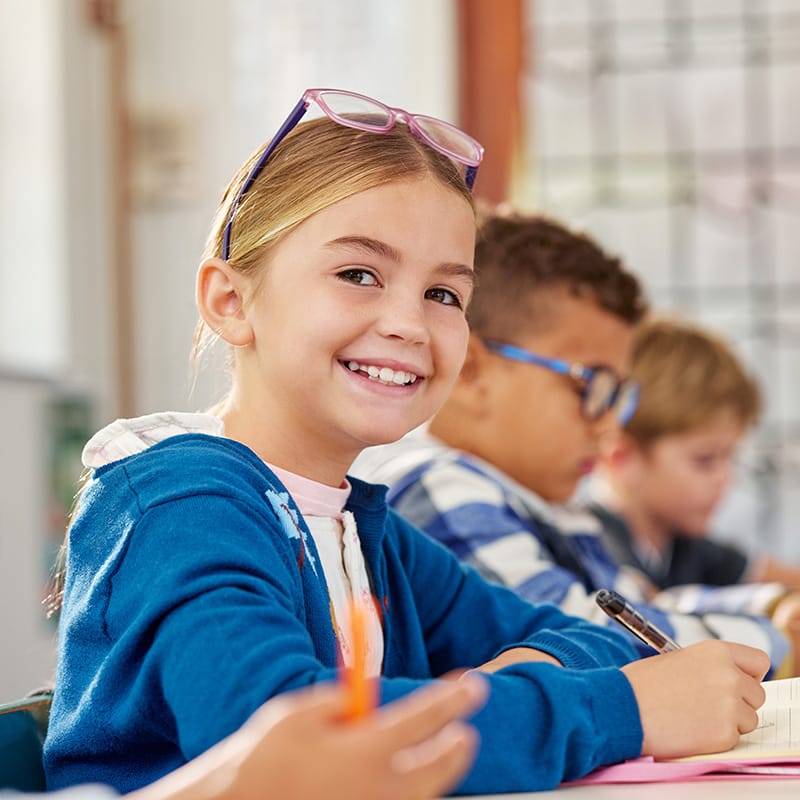Smiling young girl in a classroom, highlighting Trillium Estates amenities with access to quality education and local schools.