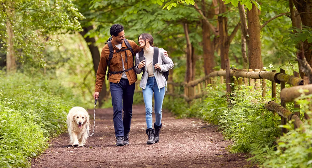 Couple walking with their dog on a lush green trail, highlighting the serene outdoor spaces within the Trillium Estates community