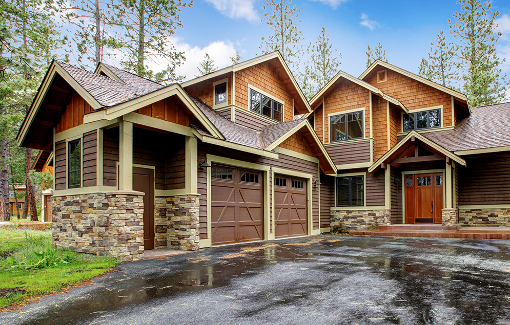 Trillium Estates house with natural stone accents, wooden siding, and large windows surrounded by tall trees and a serene environment.